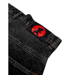 Black denim jeans with a red and black silhouette patch of a character on the waistband