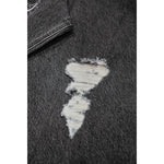 Close-up of dark gray denim fabric with a distressed hole revealing white threads