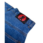 Close-up of blue denim jeans with a black patch featuring a red circle and a black character silhouette