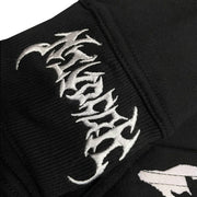 Close-up of black fabric with white Gothic-style embroidered text on ribbed cuff