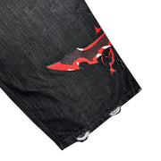 Black denim jeans leg with red and black flame patch and distressed holes