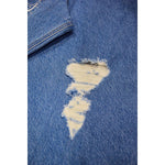 Close-up of ripped blue denim jeans with frayed edges and white threads visible